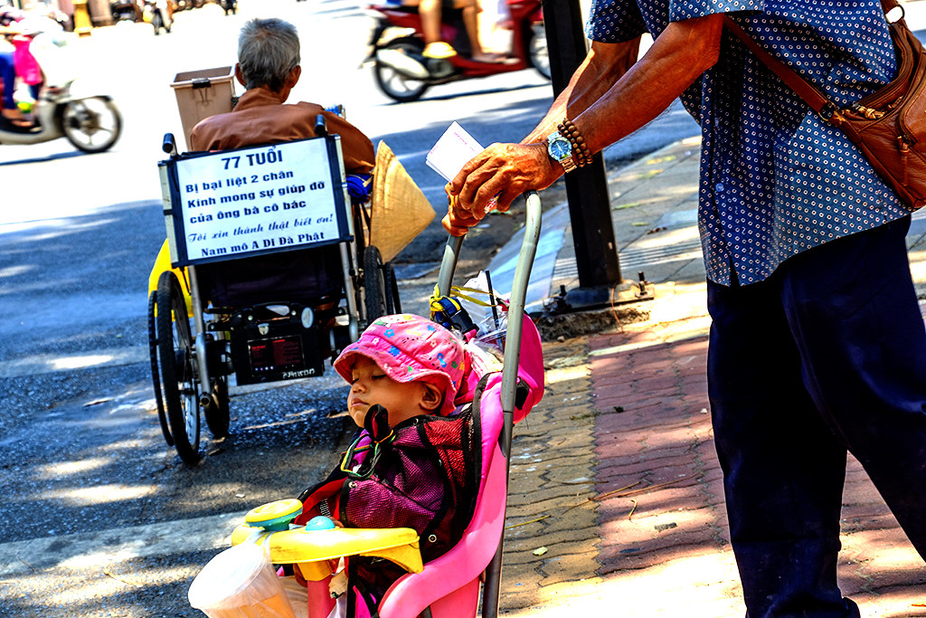 Itinerant seller of lottery tickets pushing baby in stroller in extreme heat on 4-27-24--Vung Tau copy
