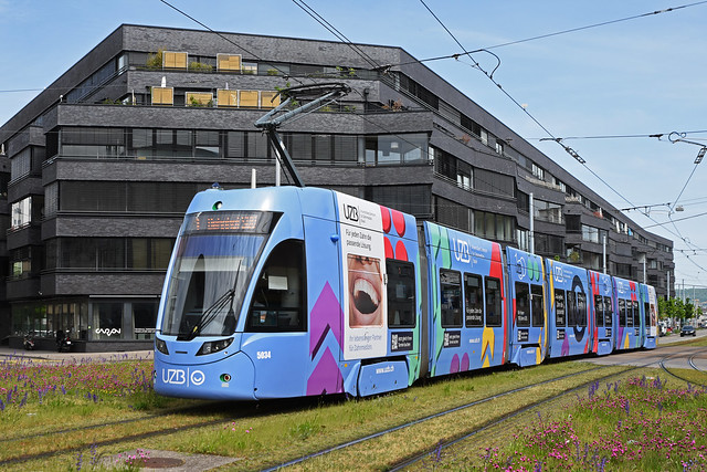Be 6/8 Flexity 5034 mit der Werbung für Universitäres Zentrum Basel für Zahnmedizin (UZB), auf der Linie 1, überquert am 29.04.2024 den Lothringerplatz.