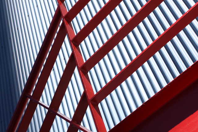 Architectural geometry: red railing, steel wall, and shadows