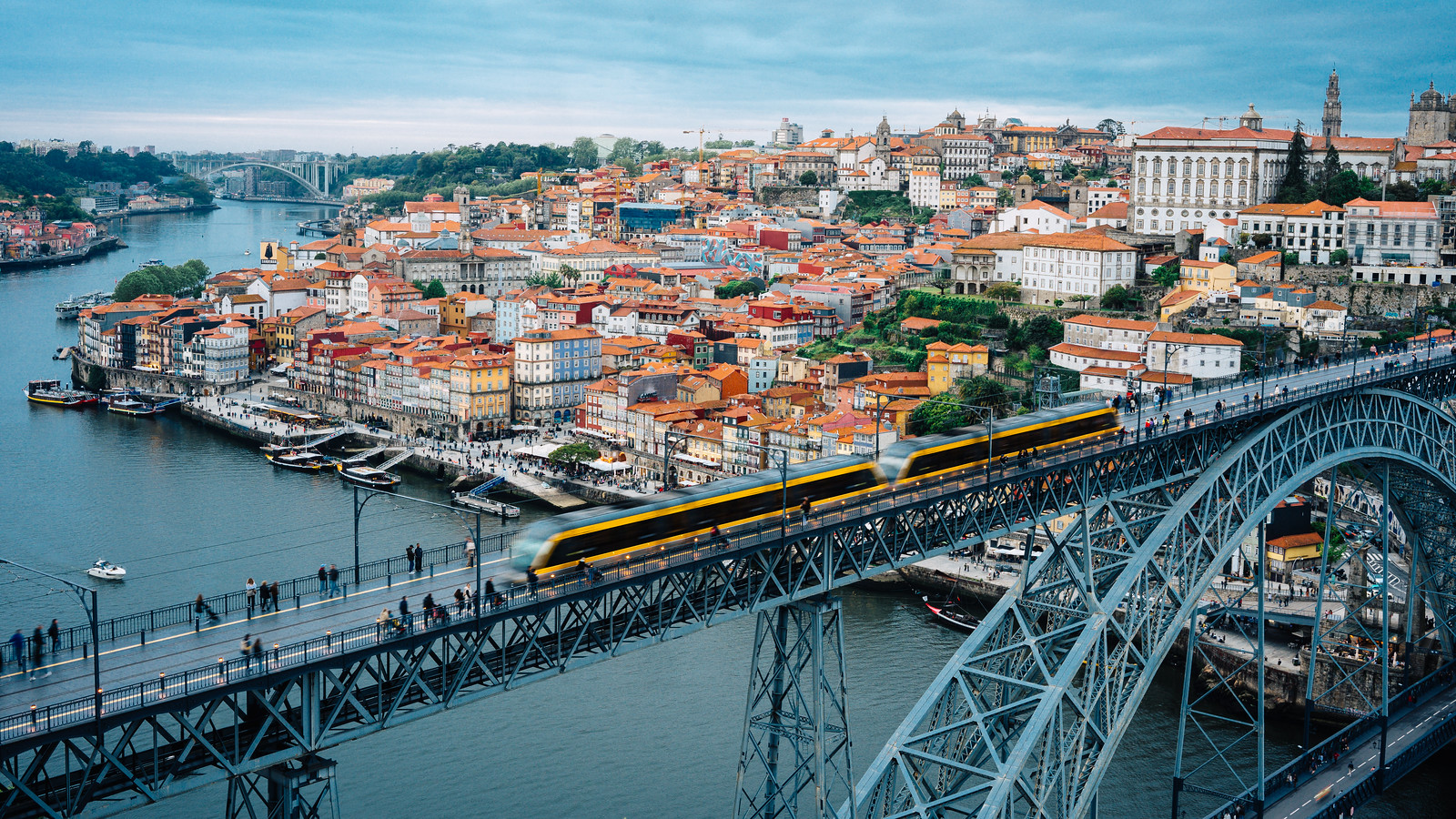Iconic Dom Luís I Bridge with Yellow Tram Crossing Over the Bustling Porto Cityscape