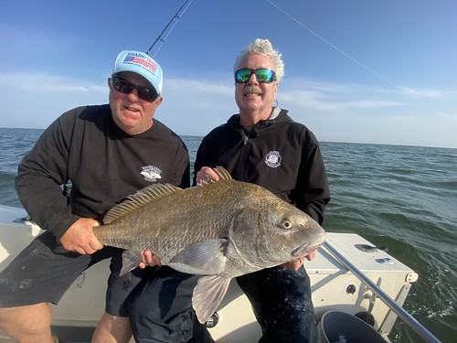 Photo of two men in a boat holding a fish