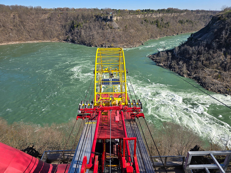 The Aero Car which is red and yellow, seen from above. Below, you can see the white rapids of the river.