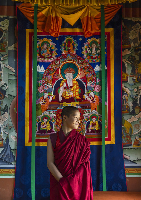 Bhutanese young monk in front of a thangka inside Nyenzer Lhakhang, Thedtsho Gewog, Wangdue Phodrang, Bhutan