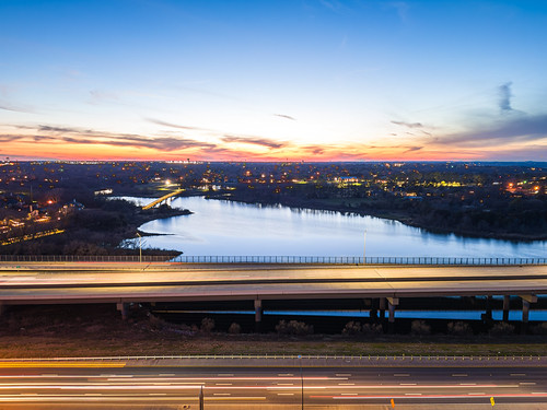 Sunset Over Urban Waterfront by Howard Le, aerial view sunset skyline cityscape waterfront highway apartment complex river lake marina golden h