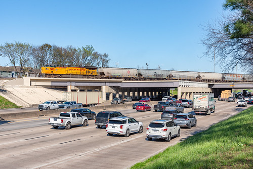 Over the Freeway by Christopher Parma, With a borrowed UP AC4400 up front, a CPKC grain train crosses the long, acute bridge over I-10 on U