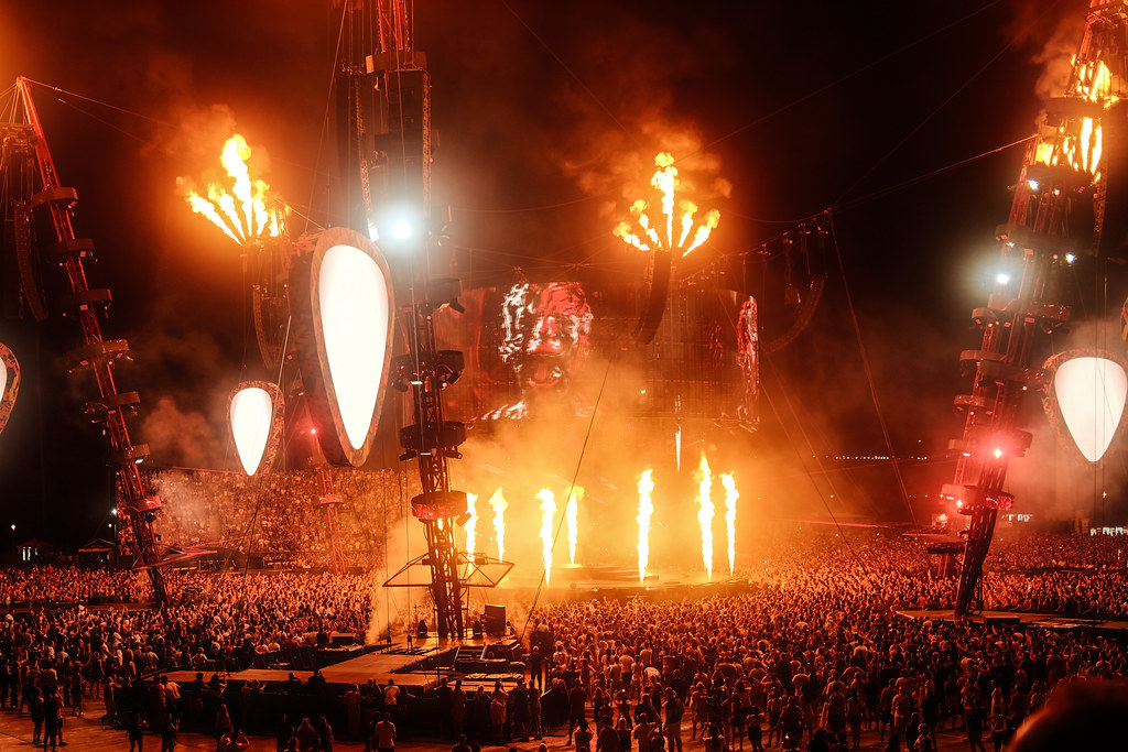 Excitement fills the air as a large crowd gathers at a music festival under a dark sky