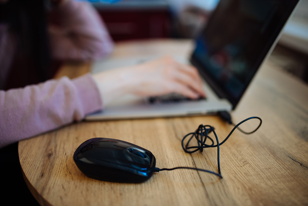 A black computer mouse lies beside the laptop, suggesting a comfortable workspace