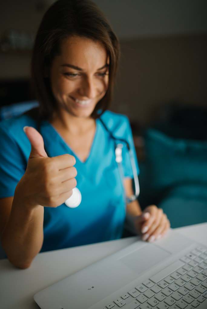 Medical professional shows approval while interacting online in a bright, modern office setting