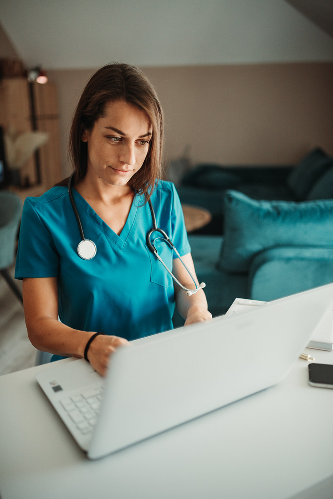 Healthcare professional focuses on computer work in a modern office setting during daytime hours