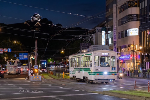 『Castle on the Hill』 by Carlos Ferran, The city of Kumamoto is one of three cities in Kyushu employing a robust streetcar system. An added 