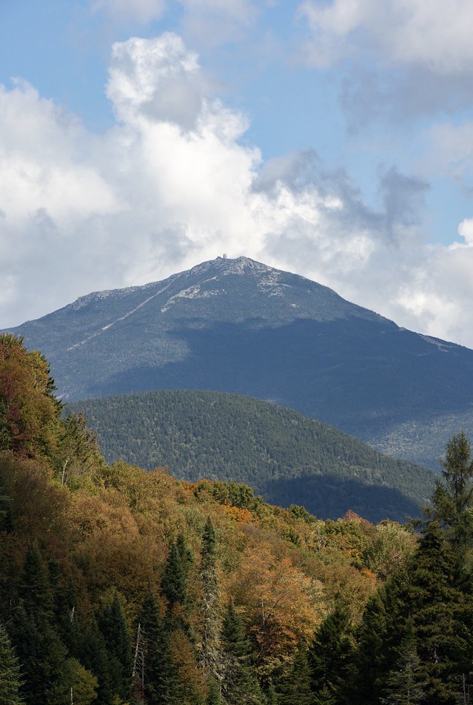 Whiteface rises behind a forested ridge while the hardwoods in front have turned rust and gold among dark spruce.