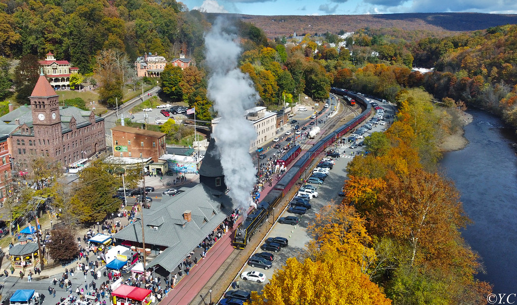 The town's depot, courthouse and mansions sit beside the river among orange, gold and green trees, with a steam train in the station.