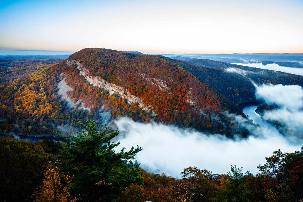 Mount Tammany's slopes are rust, red and orange from top to bottom, with fog filling the river gap below at sunrise.