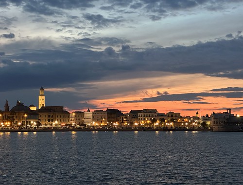 City skyline at dusk with illuminated buildings reflecting on the water, Bari, Apulia, Italy, May 2025 by sergei.gussev, Bari's skyline at dusk, with a picturesque view of illuminated buildings lining the waterfront. The