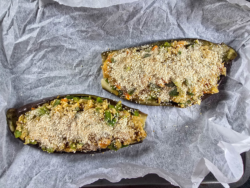 The stuffed aubergines inside a tray, on baking paper, just before they are put in the oven