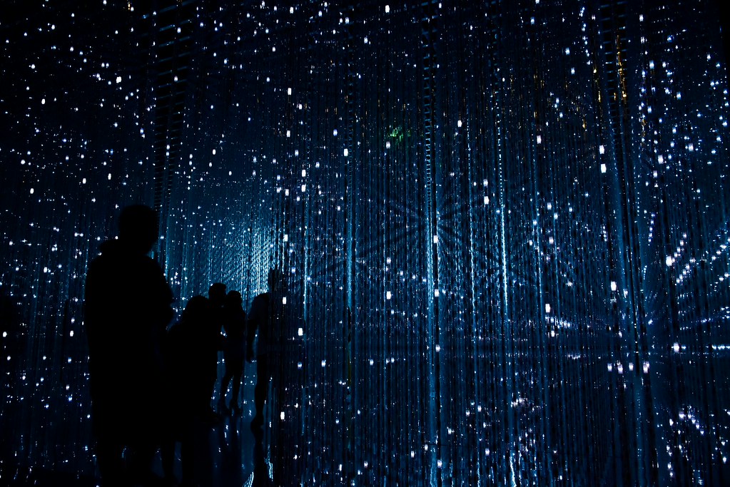 People in dark room with blue and white light display