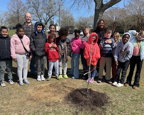 Forester with a group of children at a freshly planted tree
