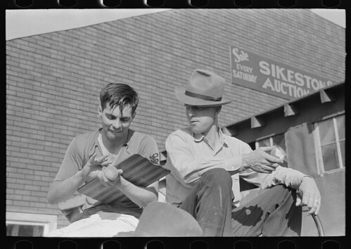 Fruit auctioneer and clerk eating peaches in front of livestock pavilion, Sikeston, Missouri (LOC) | by The Library of Congress