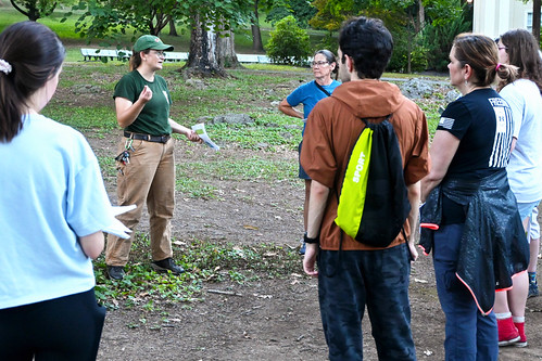 People gathered in a park as a forester talks about seeds
