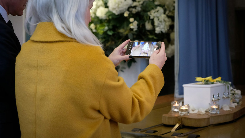 A person taking a picture of a coffin at a funeral