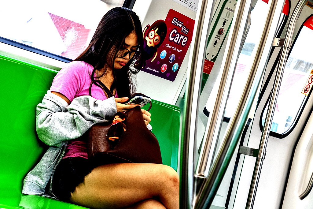 Young woman on subway looking at phone, on 9-15-26--Singapore copy