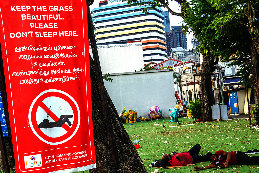 Two men lying on fake grass, one sleeping, in Little India on 9-18-26--Singapore copy
