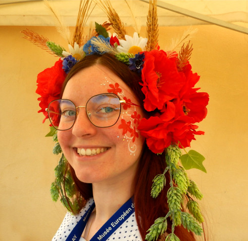 At the Musée de la Biere in France, the young woman manning the information booth wears a wreath of red flowers with green hop flowers dangling off the edges on her head