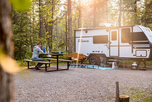 Camper sits at a picnic table with an RV at Gooseberry Campground