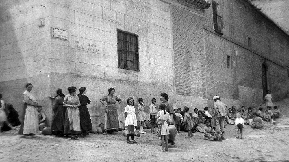 Mujeres y niños con cántaros en la cola de la fuente de la plaza Juan de Mariana (junto a Madre de Dios) hacia 1920. Fotografía de los británicos Charles y Henry Thomas. Colección de José Lucas Segarra.