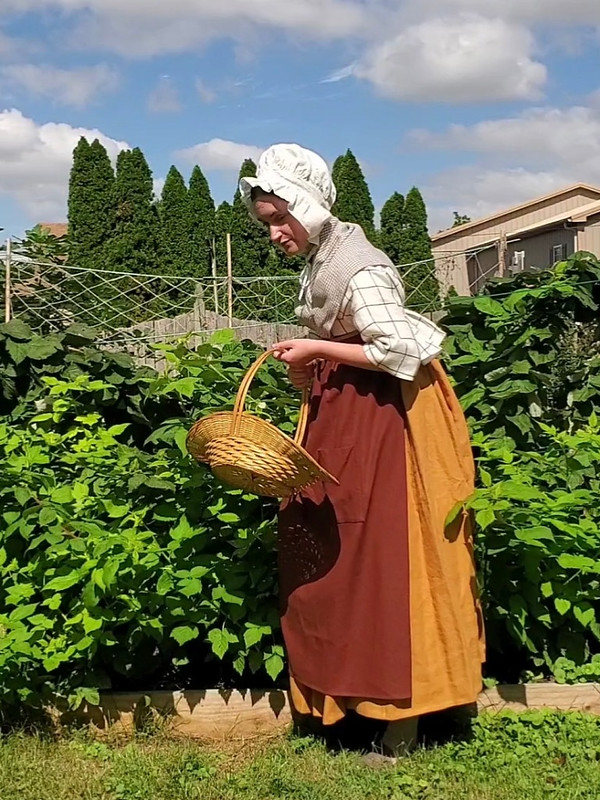 image of a woman in short gown and petticoat holding a flat basket
