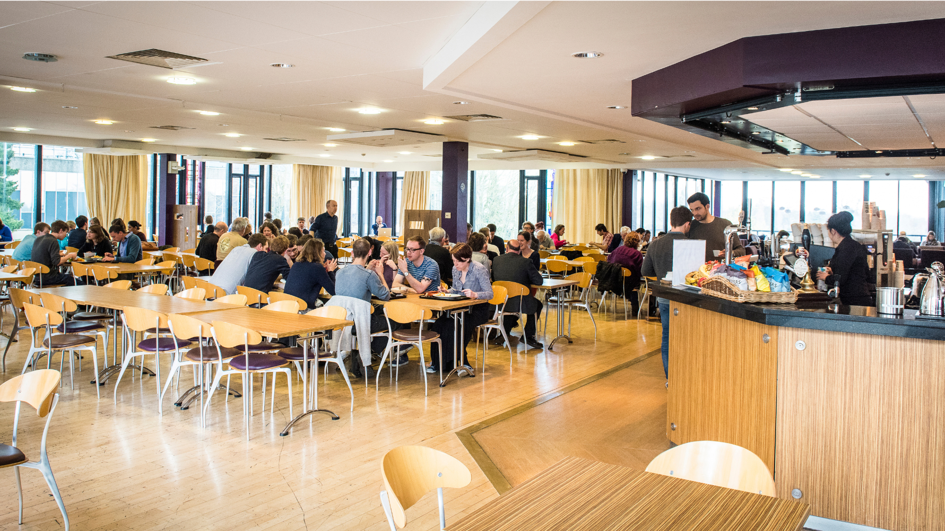 A busy cafe with lots of people eating and drinking.