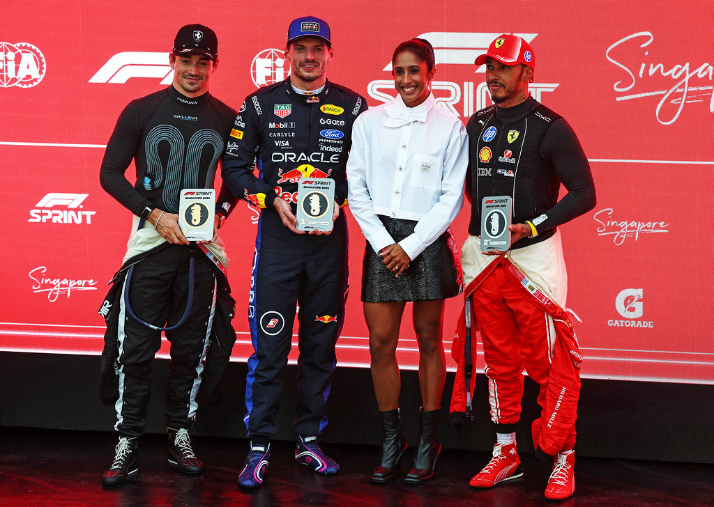 SINGAPORE, SINGAPORE - OCTOBER 10: Sprint winner Max Verstappen of the Netherlands and Oracle Red Bull Racing, Second placed Lewis Hamilton of Great Britain and Scuderia Ferrari, Third placed Charles Leclerc of Monaco and Scuderia Ferrari and Veronica Shanti Pereira pose for photos in parc ferme during the Sprint ahead of the F1 Grand Prix of Singapore at Marina Bay Street Circuit on October 10, 2026 in Singapore, Singapore. (Photo by Mark Thompson/Getty Images) // Getty Images / Red Bull Content Pool // SI202610100354 // Usage for editorial use only //