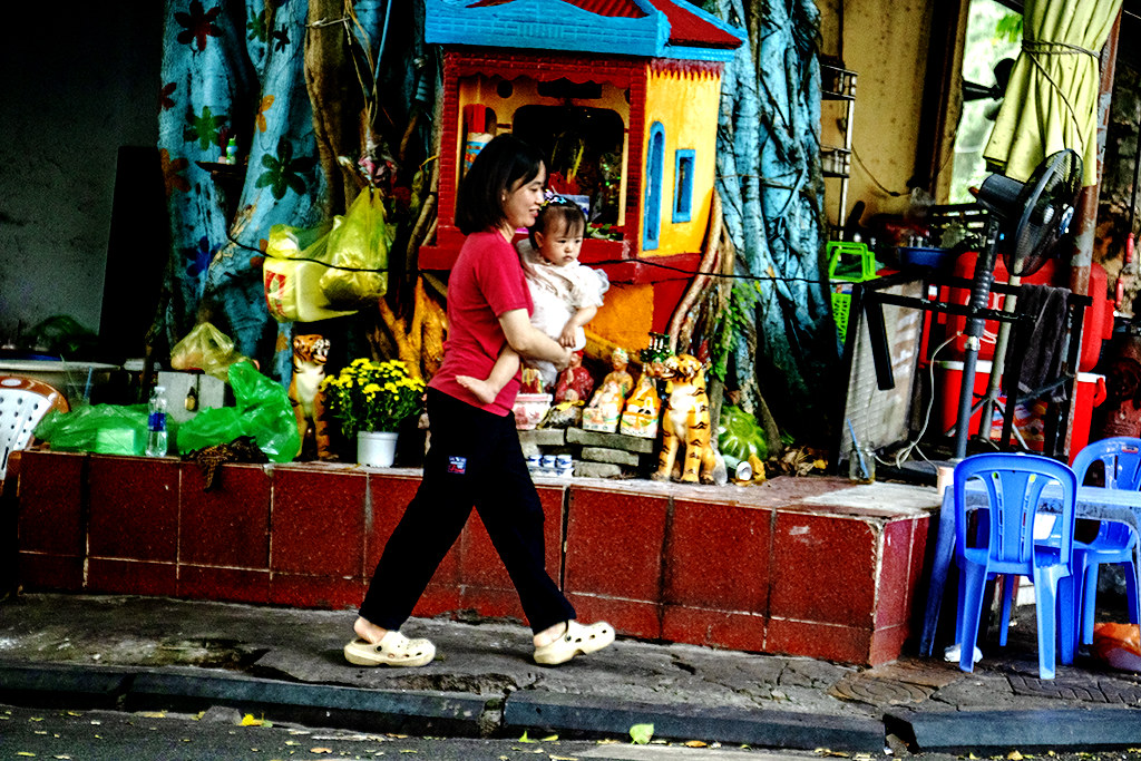 Woman carrying baby walking by shrine with goddesses and tigers on 10-11-26--Vung Tau copy