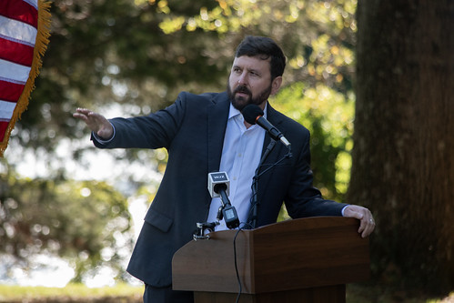 Man speaking at a podium in a wooded area