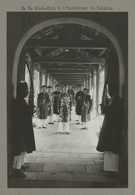 1922 - Sa Majesté Khai Dinh, en promenade dans l'intérieur du palais. Des gardiens mystérieux veillent dans l'ombre.