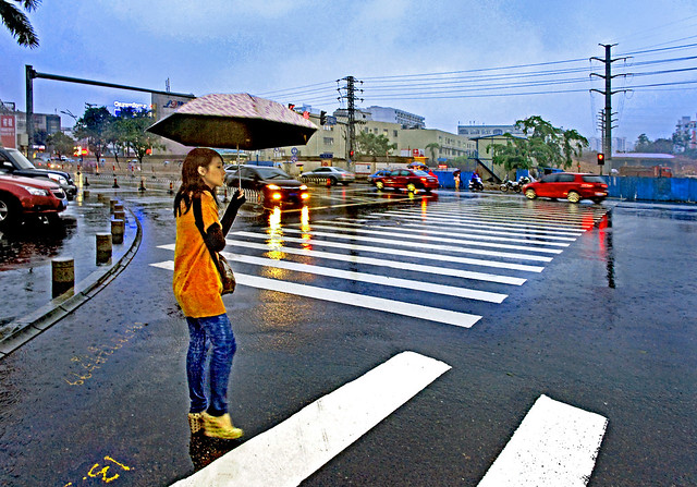 China 2011. Haikou (Hainan). The girl under umbrella in monsoon rain at dusk.