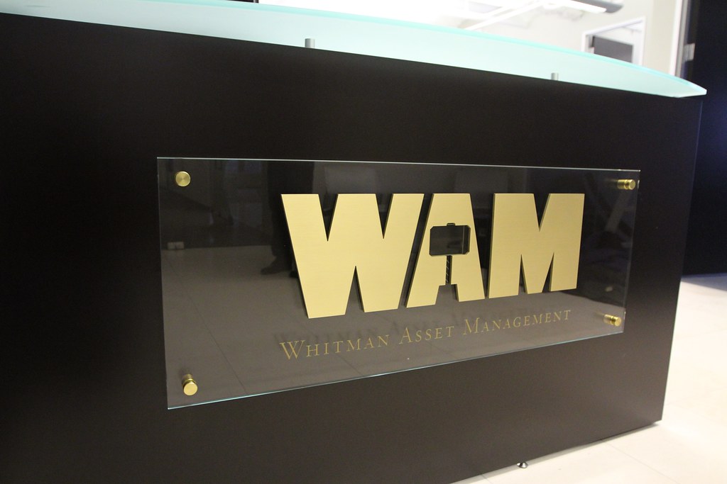 Glass panel sign with raised gold metal letters and tagline etched into face of glass