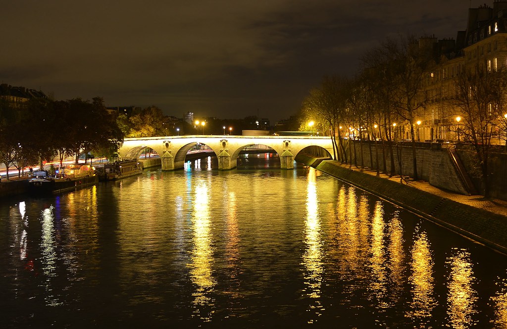 The Pont Marie lit at night over the Seine in Paris, with lamplit quays and trees