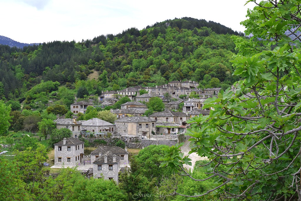 photo of a village of stone huts nestled in a lush green valley
