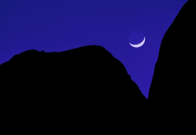 Crescent moon setting between 2 mountains