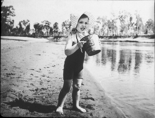 Girl (Meredith Binns) on the Murray River. The bucket advertises "Vita Brits". "Dad used them as a Christmas card called "The Sunbonnet Baby"". (Spoken by Phyllis Collie 5.12.88) - Cobram, VIC, c. 1939, by Gordon Binns | by State Library of NSW