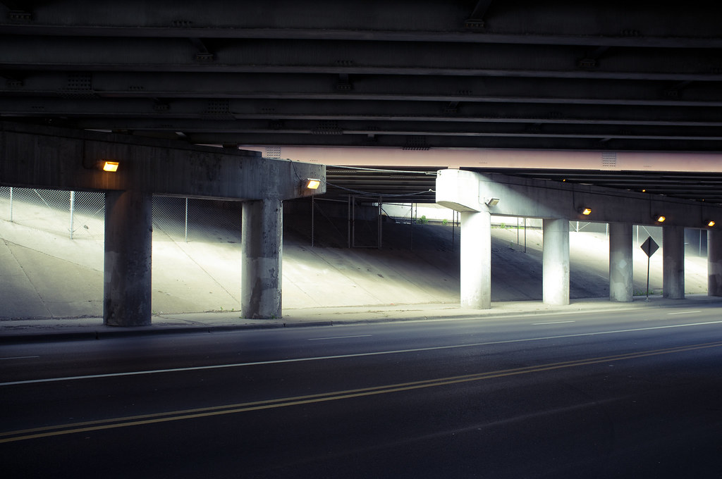 Sprawling Chicago concrete highway underpass with glowing yellow lamps and daylight washing down the embankments.