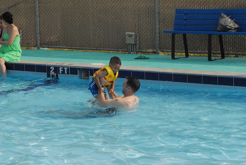 A child playing in a pool with a lifejacket on