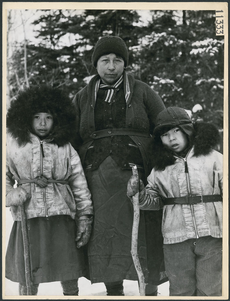 A woman and two children wearing  buckskin parkas trimmed with bear fur / Une femme et deux enfants portant des parkas en peau de daim garnis de fourrure d'ours