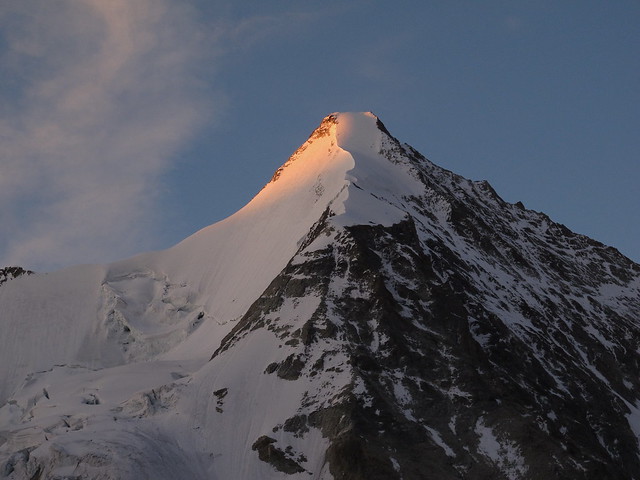 The first rays of the morning sun illuminate the summit of Obergabelhorn