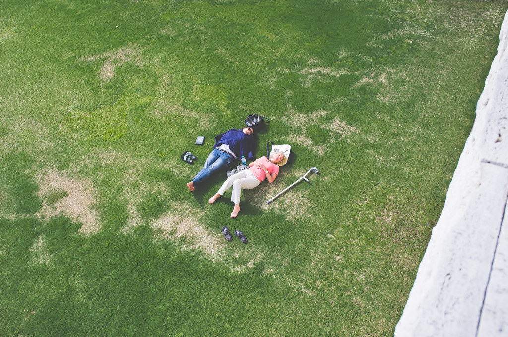 High-angle view of two people resting on their backs on a manicured green lawn at the Getty Center.