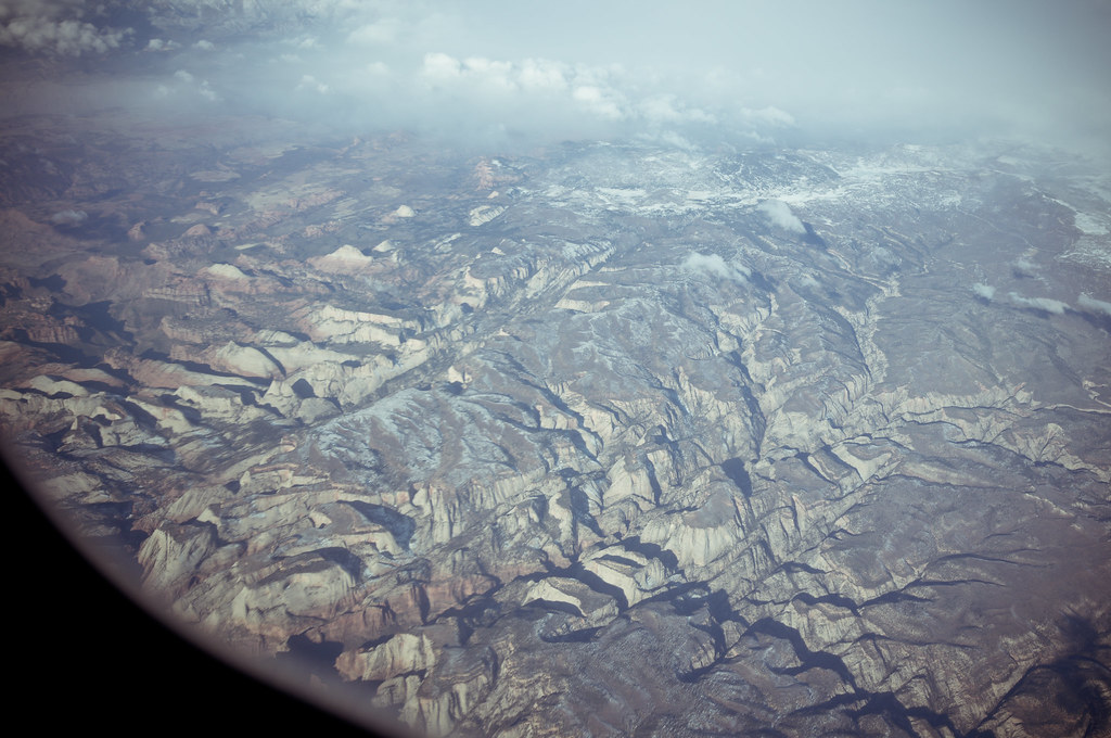 Aerial view of snow-dusted mountain ridges, mesas, and desert canyons over Nevada en route to California.