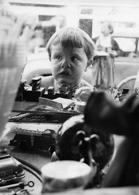 Kind bij etalage speelgoedwinkel / Child at the shop-window of a toy shop