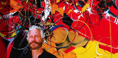 Artist standing before a vivid red and yellow abstract