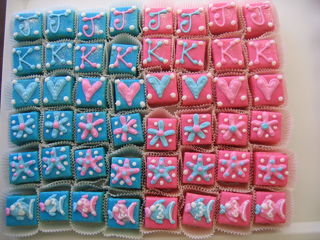 Vanilla petit fours dipped pink & blue with piped baby shower themed designs